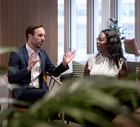 En man och en kvinna i affärskläder samtalar i en modern kontorsmiljö, med fokus på rådgivning och stöd inom CFO-coachning hos Grant Thornton